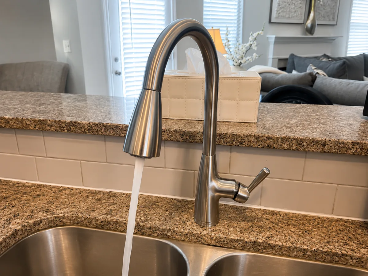 New brushed nickel pull-down kitchen faucet installed by A&G Plumbing over a stainless sink in a Metro Atlanta home